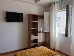 a bedroom with a tv on the wall next to a window at La casa de la abuela in Narón