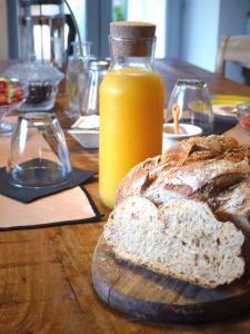 a table with a loaf of bread and a bottle of orange juice at Chambres d'hôtes l'allegra in Saint-Euphrône