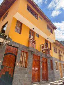 a yellow building with wooden doors on a street at Sunshine in Ollantaytambo