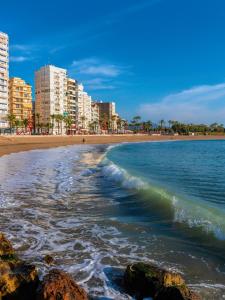 a beach with rocks in the water and buildings at Casa junto al mar in Vinarós