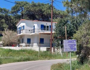 a white house with a sign in front of it at Sea & Sun Ikaria in Gialiskari