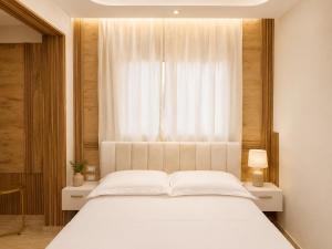 a bedroom with a white bed and a window at Flogeri in Vlorë