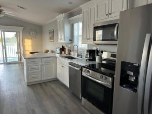 a kitchen with white cabinets and black appliances at Lake Front, Beach Retreat in Fort Myers Beach