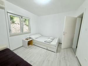 a white room with a bed and a window at Green House Cuprija in Stolac