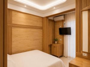 a bedroom with a bed and a flat screen tv at Flogeri in Vlorë