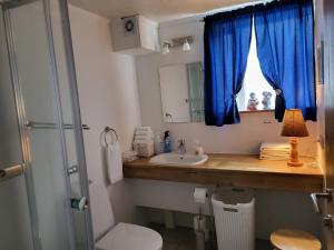 a bathroom with a sink and a window with blue curtains at Holiday Guesthouse in Stykkishólmur