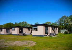 a row of mobile homes in a field with grass at 't Veldhuisje 110 - naast het bos, honden toegestaan in Anloo