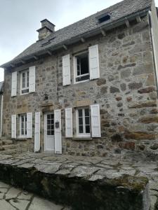 an old stone house with white shuttered windows at Maison typique auvergnate in Saint-Jacques-des-Blats