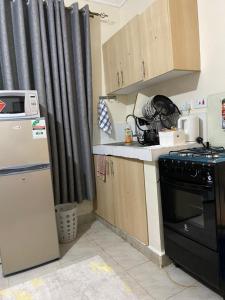 a small kitchen with a stove and a refrigerator at Ruaka Karington Studio in Ruaka