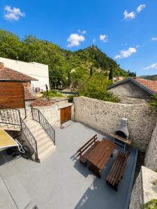 a patio with two benches and a stone wall at Green House Cuprija in Stolac