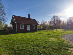 a small red house on a green field at The Red Butterfly 2 cottage in Månstad