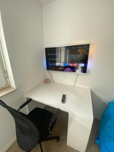 a white desk with a chair and a television on a wall at Apartment am Paradiespark in Jena