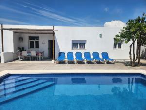 a swimming pool with blue chairs and a house at Parisito Sancti Petri - Villa amplia con piscina privada in Chiclana de la Frontera