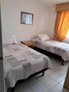 a bedroom with two beds and a picture on the wall at Apart Antofagasta in Antofagasta
