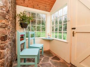 a room with two blue chairs and windows at Whitefield Cottage in Barnstaple