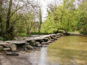 a stone bridge over a river in a park at Whitefield Cottage in Barnstaple +17 photos