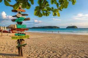 a street sign on a beach with the ocean at Hospedaje de la playa in Sámara