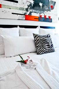 cama blanca con almohadas blancas y control remoto. en In Fashion Hotel & Spa en Playa del Carmen
