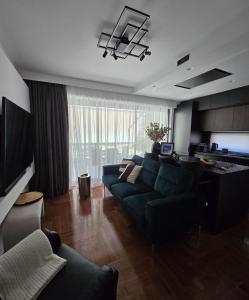 a living room with a green couch and a kitchen at Emerald Stone Apartment Varkiza in Vari