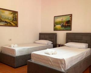 two beds in a room with paintings on the wall at Berat Private Appartment in Haxhialiu Villa in Berat