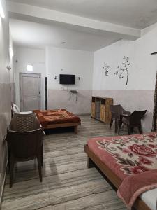a room with two beds and a table and a tv at Pinewood Sunrise Homestay Kasauli by Splendid Retreat Hotels in Kasauli