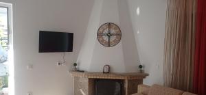 a living room with a fireplace with a clock on the wall at Sofia Comfort Apartment in Nivicë
