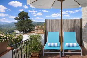 two blue chairs on a balcony with an umbrella at La Vignaredda - Residenza di Charme in Aggius