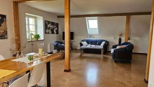 a living room with blue chairs and a table at Helle Ferienwohnung - Südeifel bei Neuerburg in Ammeldingen