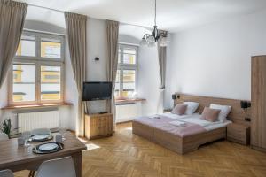 a bedroom with a bed and a table and a tv at Cracow Main Square Apartments in Krakow +61 photos