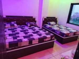 two beds in a room with pink and purple at New MORVINAND PALACE in Khātu
