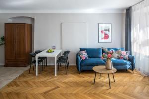 a living room with a blue couch and a table at Cracow Main Square Apartments in Krakow