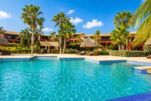 a swimming pool at a resort with palm trees at JeVakantie Spanish Water Apartments B7 and C8 with Infinity Pool near Jan Thiel in Willemstad