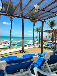 a group of blue chairs on a beach with the ocean at El Aram Imirá Beach Resort in Natal