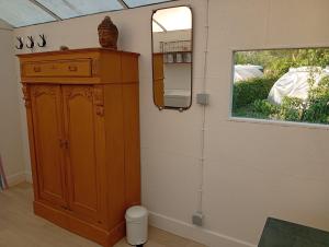 a room with a wooden cabinet and a mirror at De smishoeve "Herdershut" in Heers