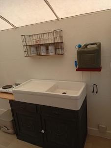 a bathroom with a sink and a television on the wall at De smishoeve "Herdershut" in Heers +14 photos