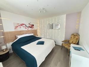a bedroom with a large bed and a chair at Au petit nid Froissart in Chimay