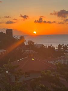 a sunset over the ocean and a house at CJ's Creole Hideaway in Castries