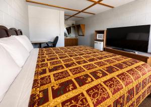 a bedroom with a bed and a flat screen tv at Skyline Motel Bartlesville Hwy 75 in Bartlesville