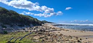a beach with a lot of rocks and the ocean at Studio 149 - Wild Coast Accommodation in Sunrise-on-Sea