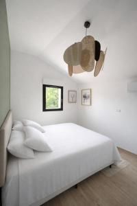 a white bedroom with a large bed and a chandelier at Le Petit Chalet in Crolles