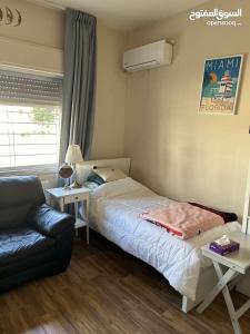 a bedroom with a bed and a couch and a window at عمان - ضاحية النخيل in Amman
