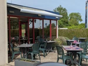 an outdoor patio with tables and chairs at a restaurant at Brit Hotel Argentan in Argentan