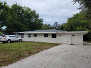 a white house with a car parked in a driveway at Manatee River Bungalow - 4 in Bradenton