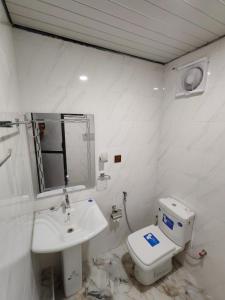 a white bathroom with a toilet and a sink at VIN Solara Farm Stay in Jaffna