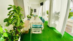 a long table in a room with green floors and plants at Villa Estrella in Dos Hermanas