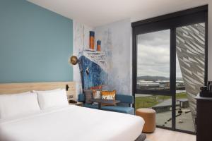 a bedroom with a bed and a chair and a window at Aloft by Marriott Belfast Titanic Quarter in Belfast