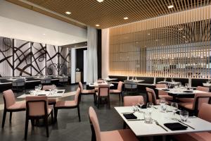 a restaurant with white tables and pink chairs at The Viv Hotel, Anaheim, a Tribute Portfolio Hotel in Anaheim