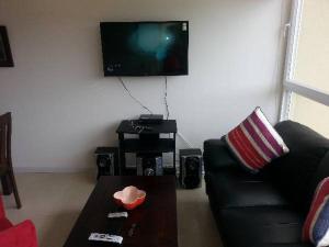 sala de estar con sofá negro y TV en Condominio Lomas de Papudo I, en Papudo