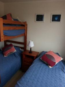 1 dormitorio con 2 camas y mesita de noche con lámpara en Condominio Lomas de Papudo I, en Papudo