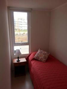 a bedroom with a red bed and a window at Condominio Lomas de Papudo I in Papudo